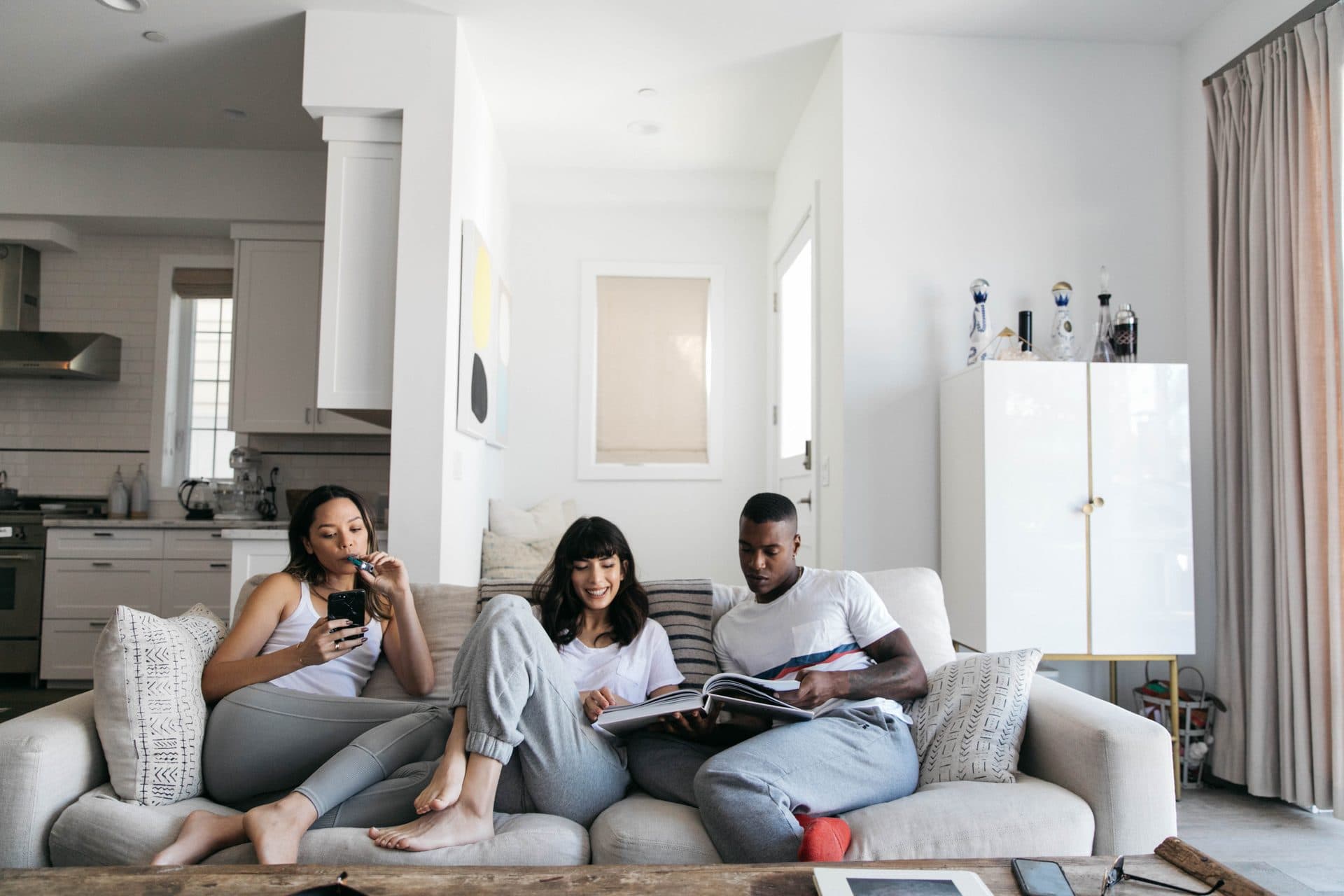 Three friends on a living-room couch, one using a personal smoke filter