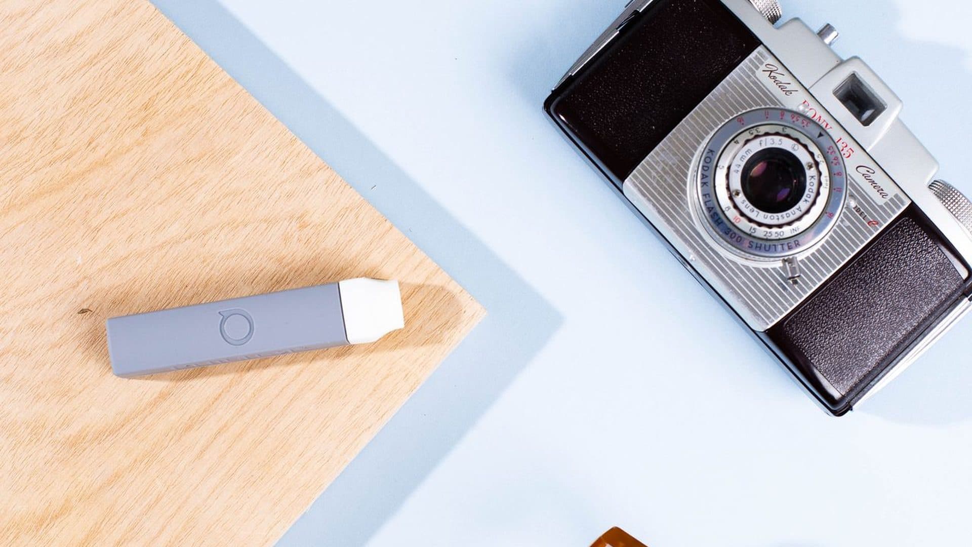 Gray POCKET personal filter beside a camera on a travel table