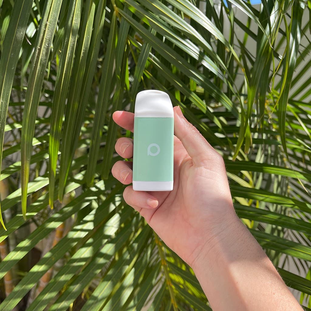 Sage PHREND personal smoke filter held in a hand in front of palm leaves